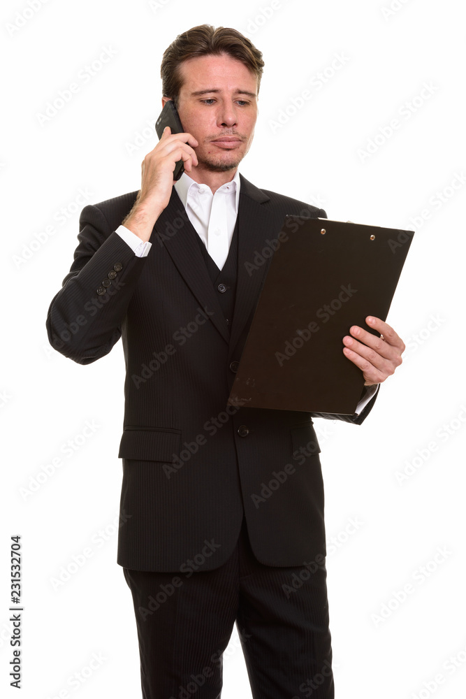 Handsome Caucasian businessman talking on mobile phone while rea