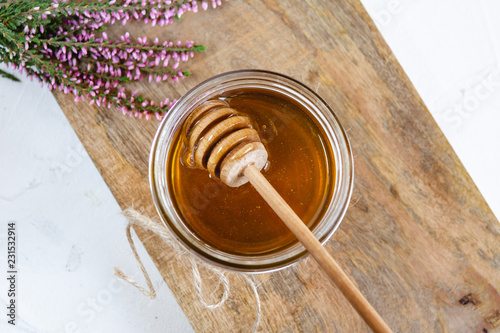 Honey in jar with fresh heather on wooden background