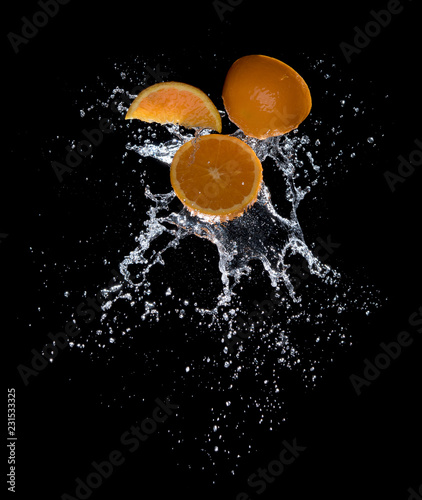 Fresh oranges with water splashes against black background