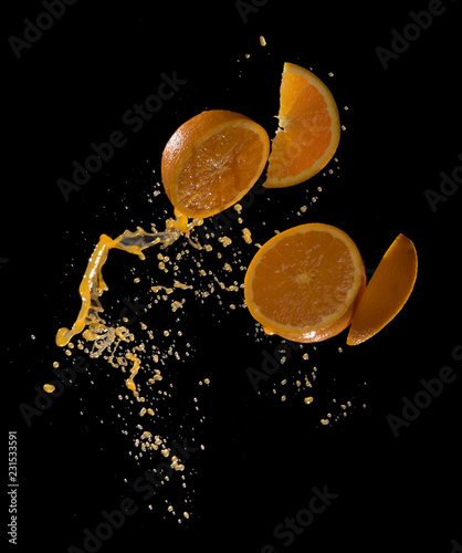 Fresh oranges with orange juice splashing isolated on black