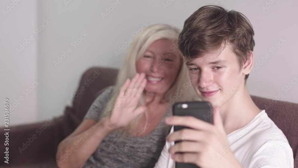 Old grandmother and adult grandson using mobile application on phone tougether seating on the sofa. Doing video call. Happy Family communication concept in 4k. Old grandmother and adult grandson using mobile application on phone tougether seating on the sofa. Doing video call. Happy Family communication concept in 4k.