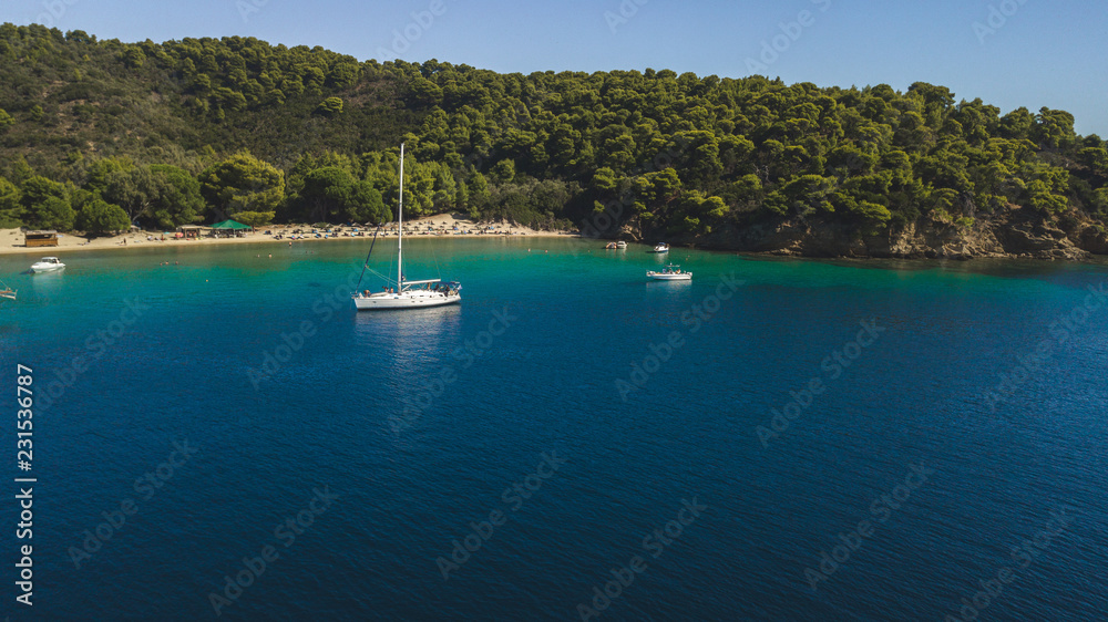 Sailboat in a beautiful bay, infront of a nice beach in Greece, Sporades Islands in the Aegean Sea - Aerial Drone Photo