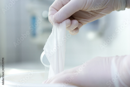 Hand with white gloves takes a white cloth out of the package