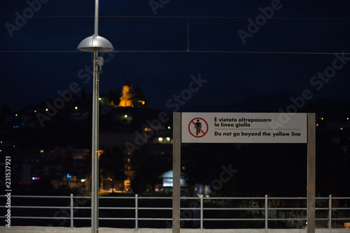 cartello di divieto di non oltrepassare linea gialla sul marciapiede di stazione ferroviaria photo