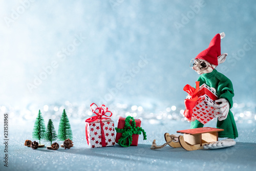 Cute Cheerful Santas Helper Elf Loading Christmas Gifts Onto Santas Sleigh. North Pole Christmas Scene. Santas Workshop. Elf at work.