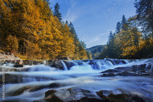 Long waterfall and river with rocks high in the mountains. Autumn mountains landscape. Idea for outdoor activities  travel.