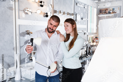 Young couple choosing new desk lamp in store