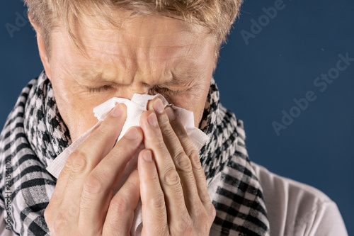 Man with cold and flu illness suffering from a headache and cough. Blue background