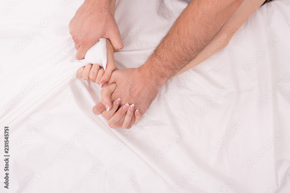 Hands of couple who making love in bed on white crumpled sheet, focus on hands Hands of couple who making love in bed on white crumpled sheet, focus on hands