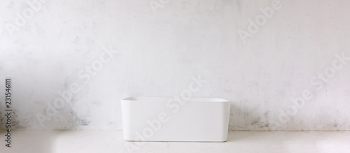 Quadro em tela Square frame of modern bathroom with freestanding white bathtub on loft rustic wall background with sun shape mirror hanging
