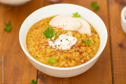 Turkish lentil bulgur soup sprinkled with pepper in a white bowl on a wooden background