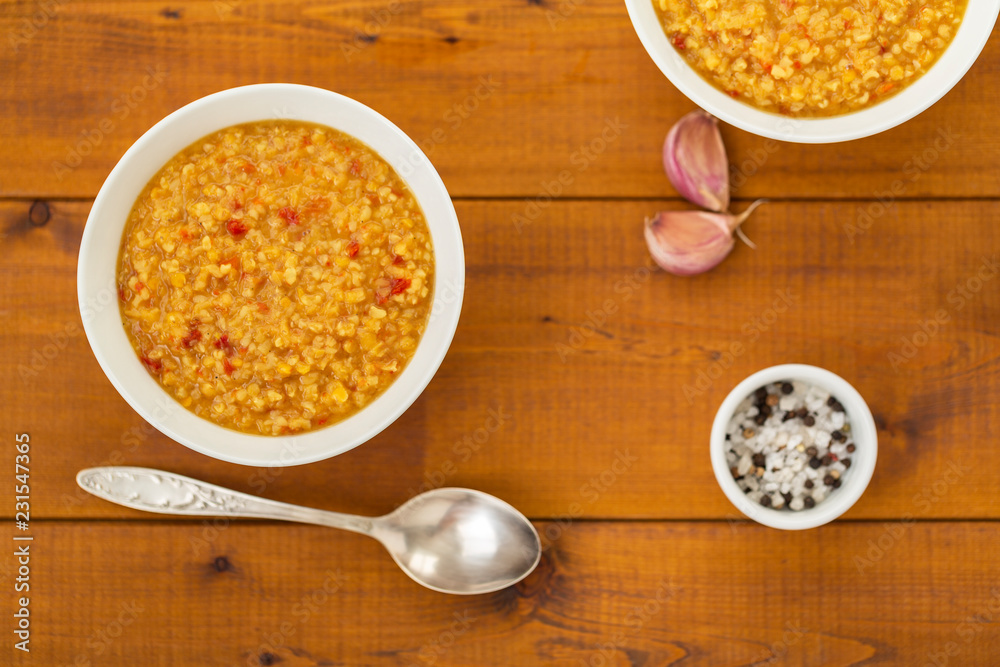 Turkish lentil bulgur soup sprinkled with pepper in a white bowl on a wooden background Turkish lentil bulgur soup sprinkled with pepper in a white bowl on a wooden background