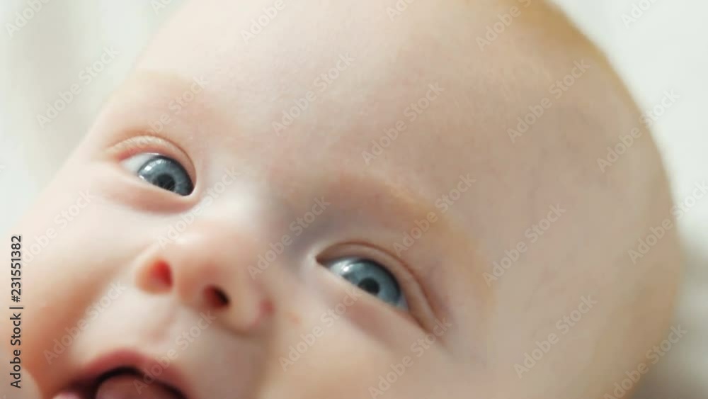 A cute little baby is looking into the camera and is happy on a white bed. A cute little baby is looking into the camera and is happy on a white bed.