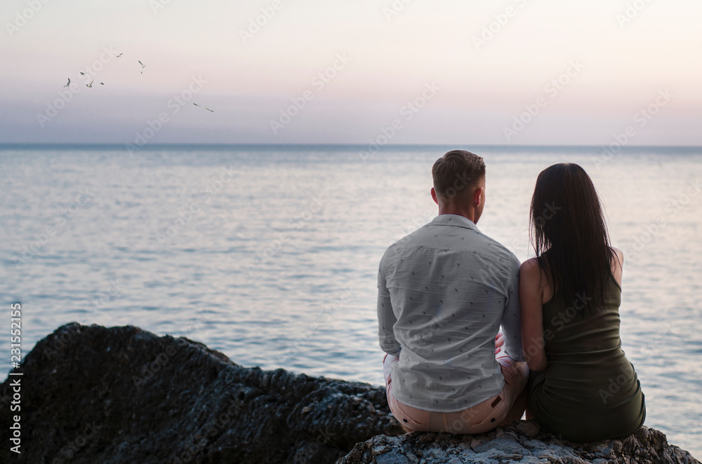young couple sitting on the beach at sunset
