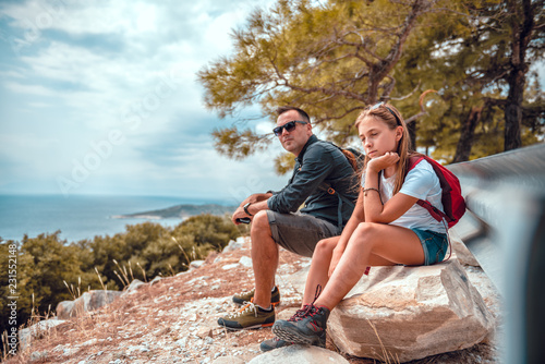 Father and daughter sitting on a rock after hiking