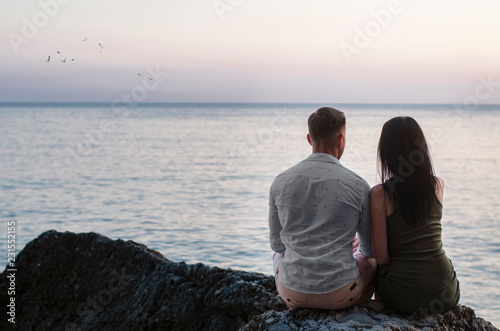 young couple sitting on the beach at sunset