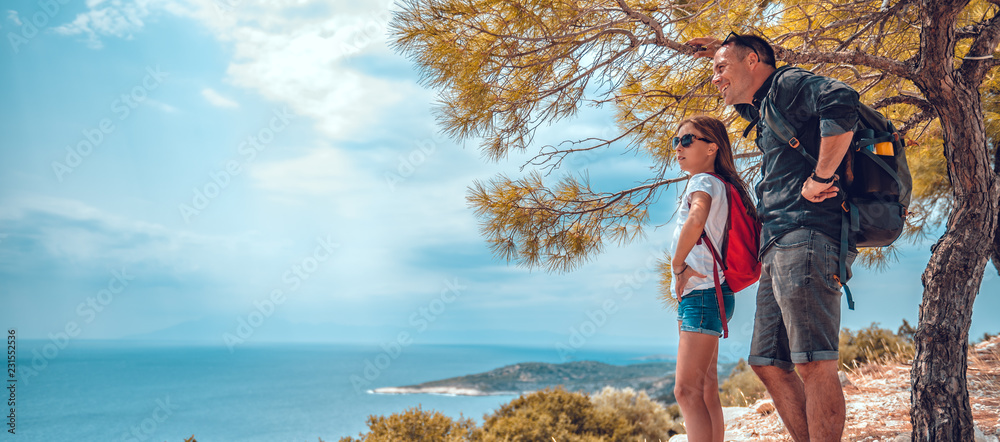 Father and daughter standing on a cliff by the sea