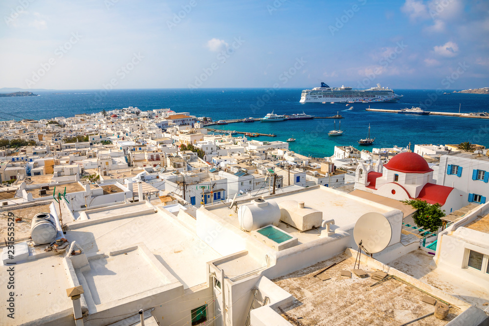 Panoramic view over Mykonos town with white architecture and cruise liner in port in Greece