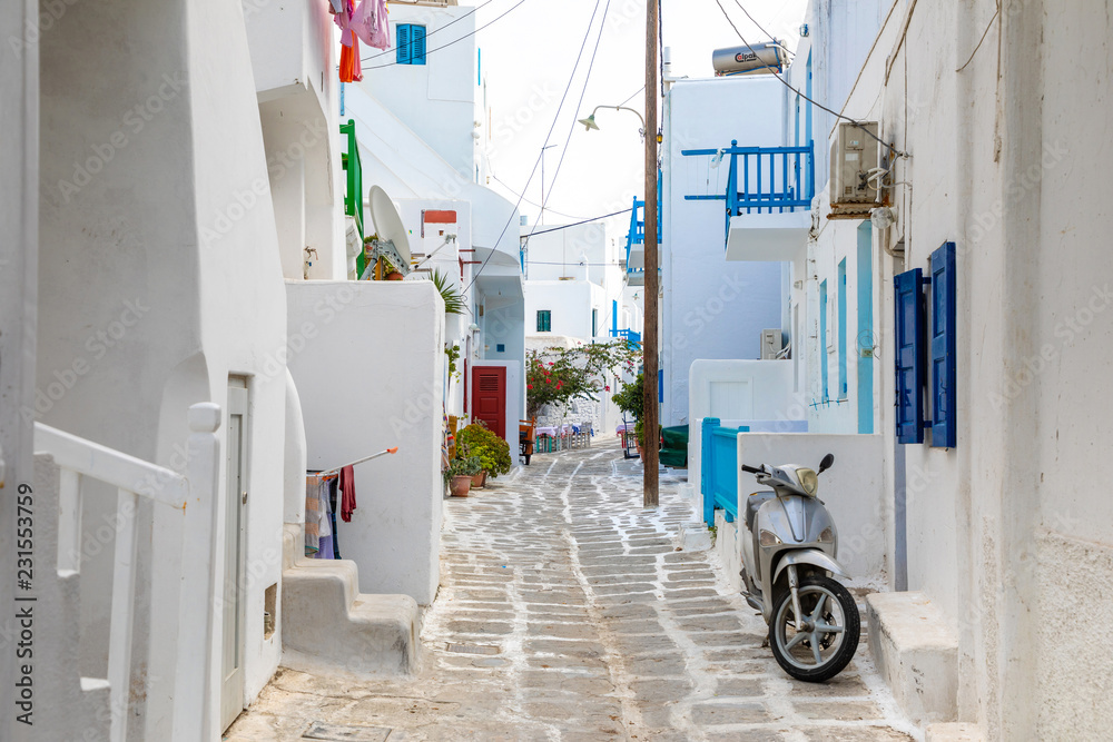 Fototapeta premium Traditional houses with blue doors and windows in the narrow streets of greek village in Mykonos in Greece