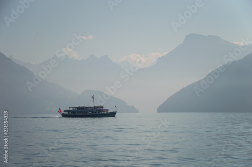 A ferry sailing on Lake Lucern between the mountains when it's foggy outside