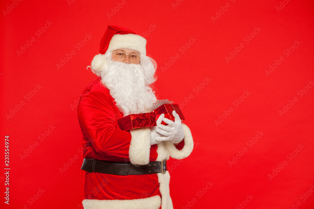Photo of Santa Claus gloved hands holding red giftbox Photo of Santa Claus gloved hands holding red giftbox