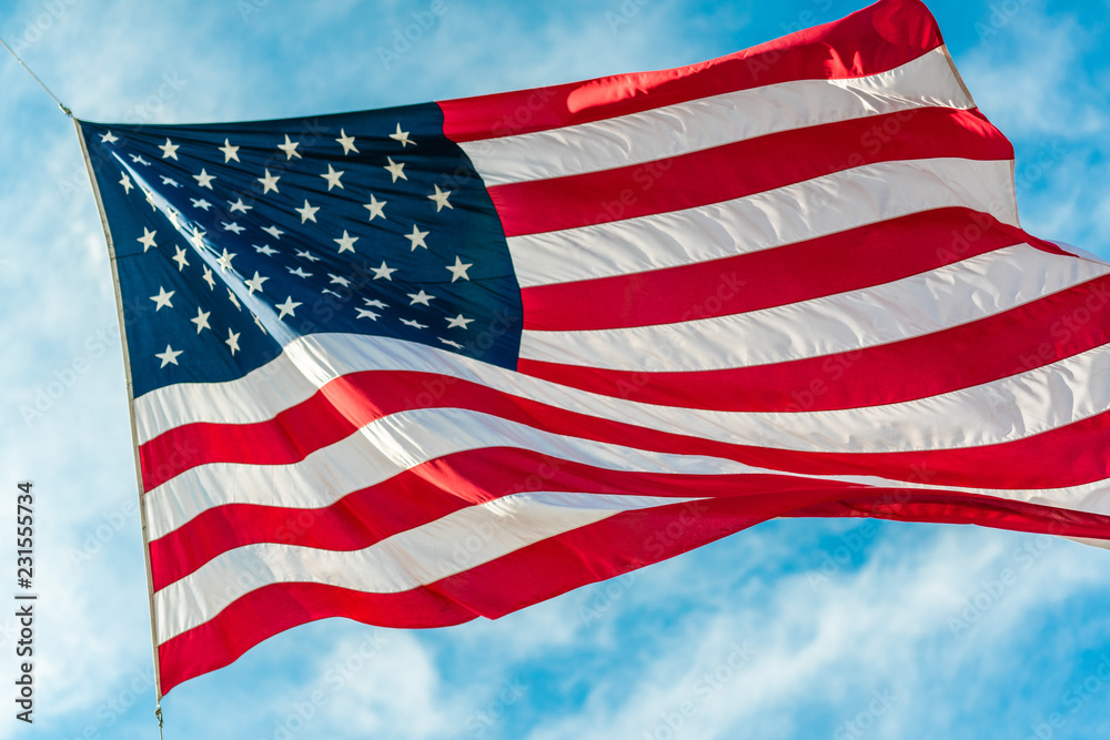 Obraz premium American flag waving in blue cloudy sky