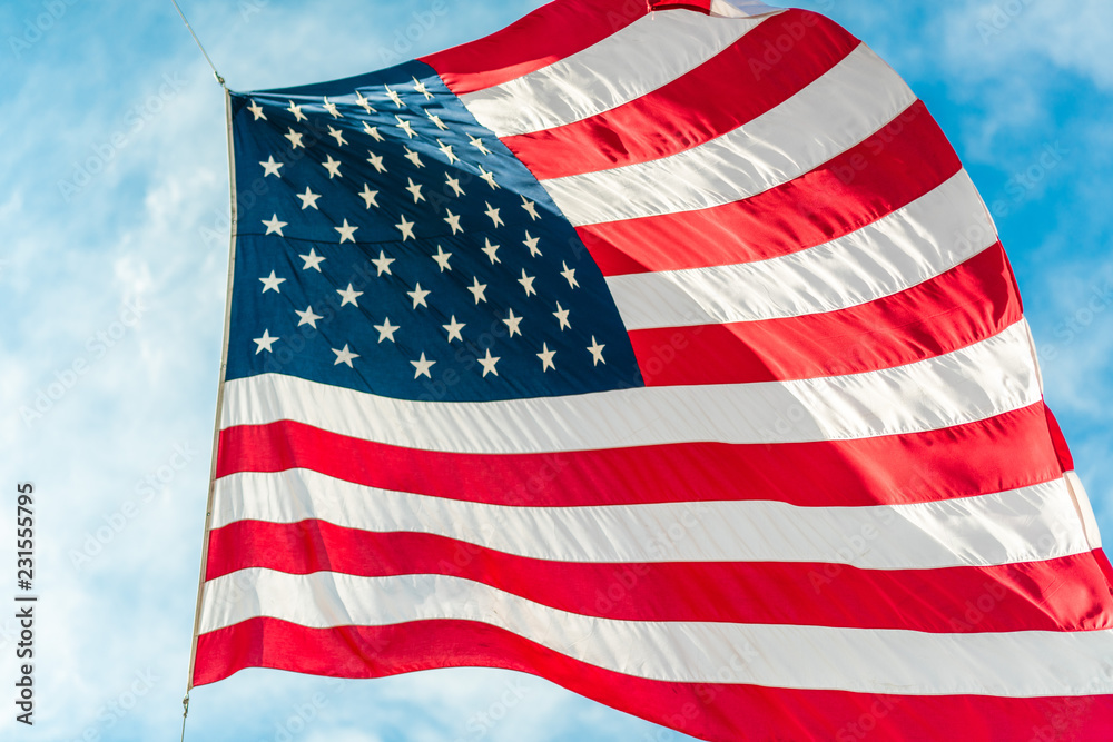 Obraz premium American flag waving in blue cloudy sky
