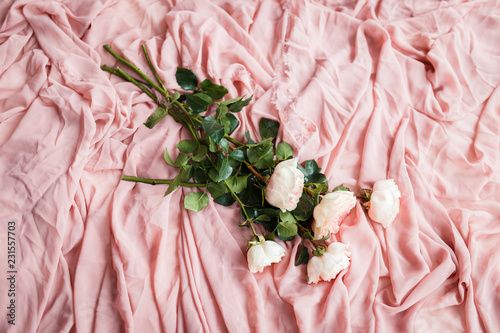 pink roses lie on delicate pink silk fabric
