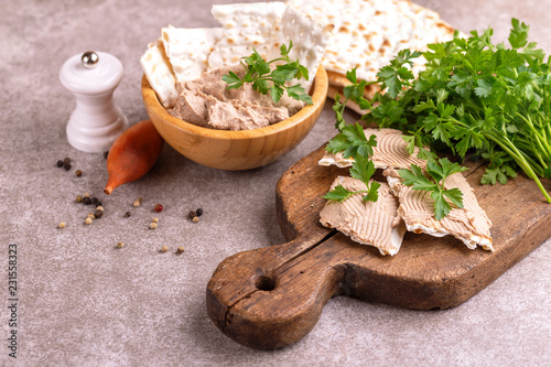 Fototapeta Naklejka Na Ścianę i Meble -  Pieces of matzah with homemade liver pate with parsley and onion on old wooden cutting board with burlap napkin. Gray marble background. Copy space