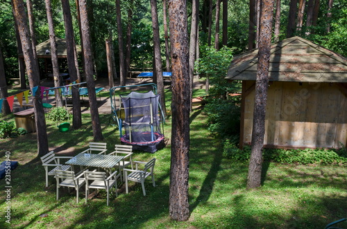 Summer child public bivouac  with table, chair, house and  jumping trampoline in the coniferous forest, near to Pasarel village, Bulgaria  photo