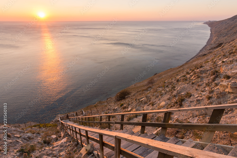 Ladder going down to the sea on a rocky cliff, sunset, Anapa, Russia