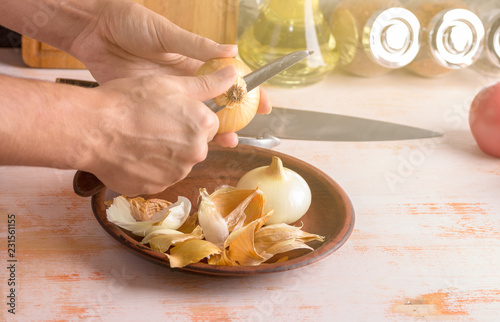Onion and knife in female hands close-up, cleaning onions. Cooking process. The concept of homemade food.