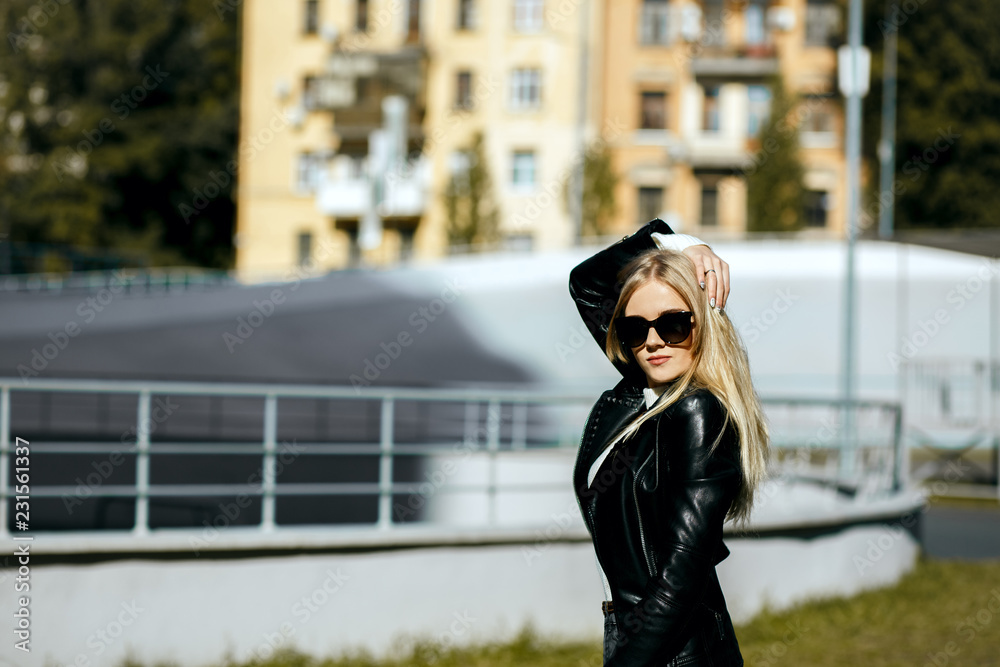 Obraz premium Closeup shot of stunning blonde model with long hair wearing leather jacket and sunglasses. Empty space