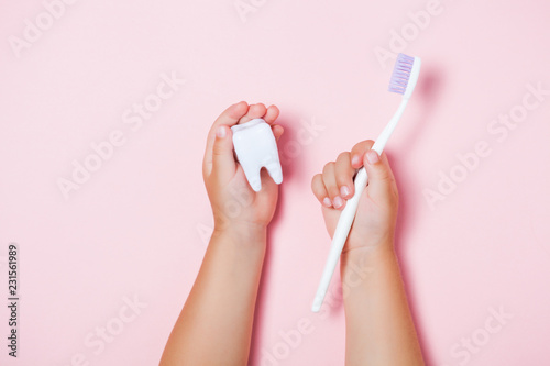 Child's hands holding big tooth and toothbrush