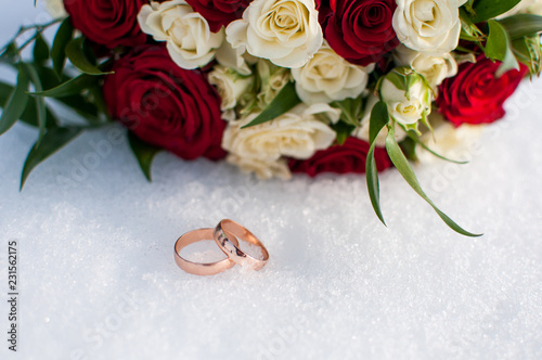 Wedding rings and colorful bouquet on the snow