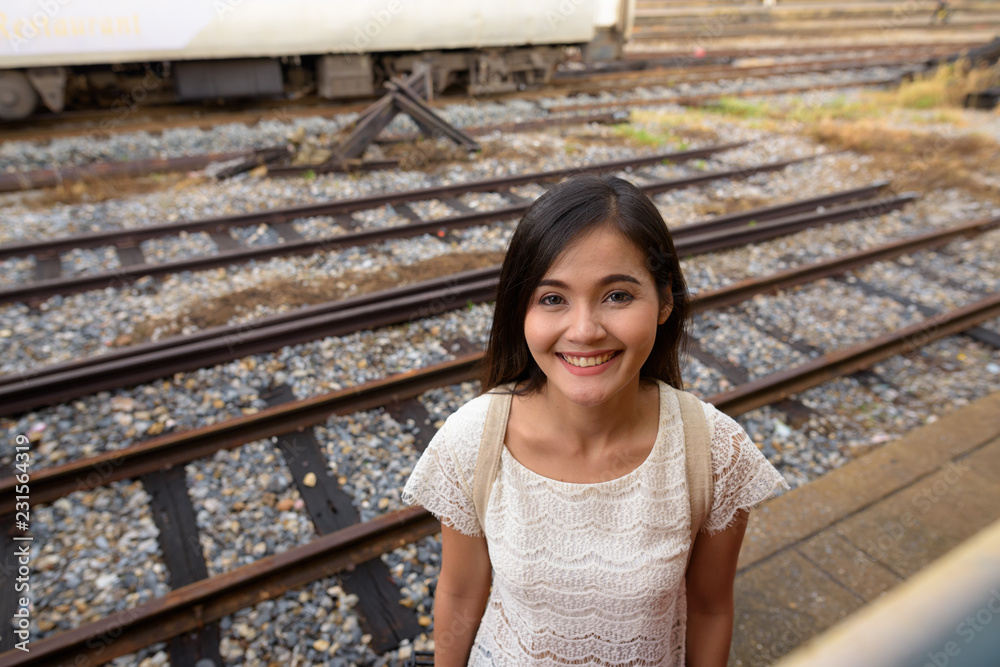 Young beautiful Asian tourist woman smiling and looking to train