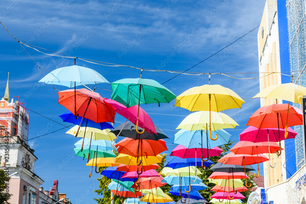 Different colorful umbrellas hanging over the street against sky