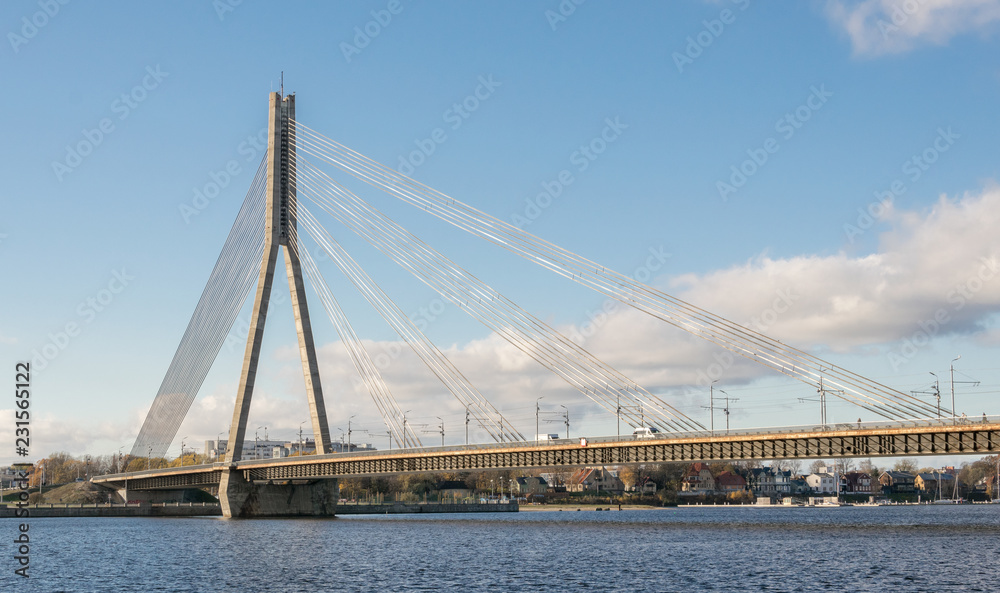Сable bridge over the river Daugava in Latvia on the blue sky and white clouds background. Cable bridge over the river.