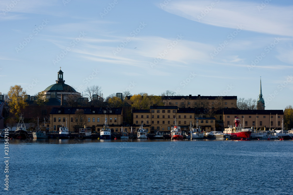 A sunny autumn morning view in Stockholm harbour, Skeppsholmen island with boats an landmarks