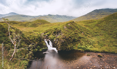 Chute d'eau en pose longue en Ecosse avec des collines, des arbres et des nuages en été