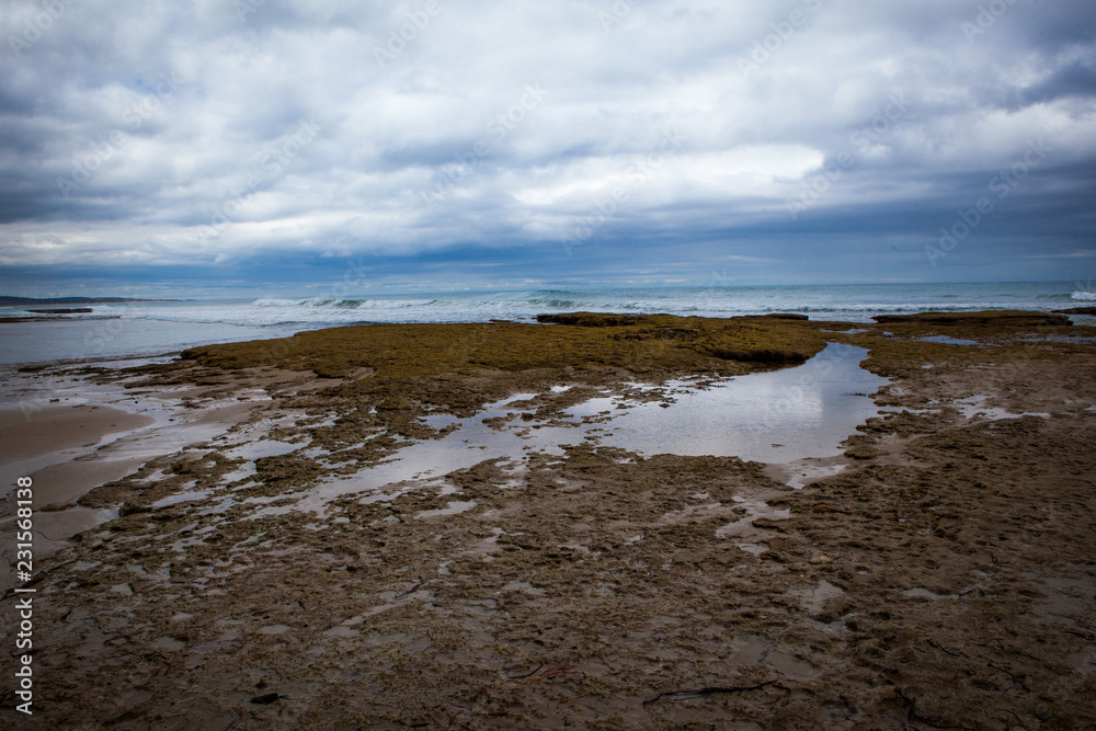 Cliff and rocky beach on a beautiful cloudy day in the middle of Great Ocean Road, Victoria, South Australia.