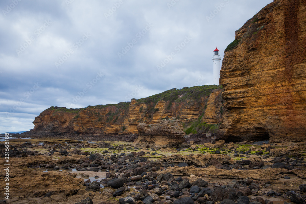 Cliff and rocky beach on a beautiful cloudy day in the middle of Great Ocean Road, Victoria, South Australia.
