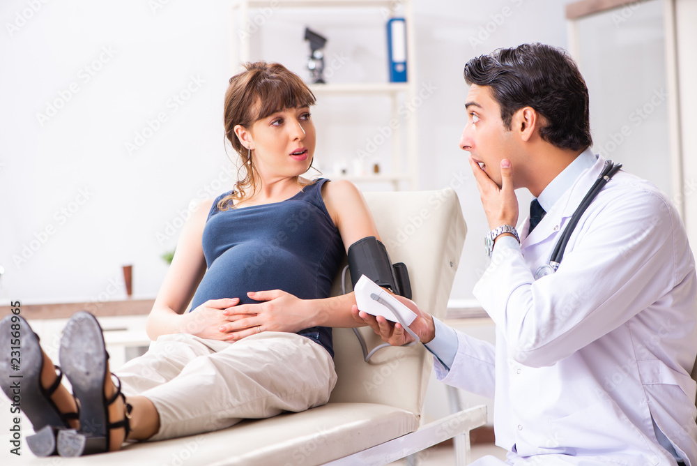 Young doctor checking pregnant woman's blood pressure