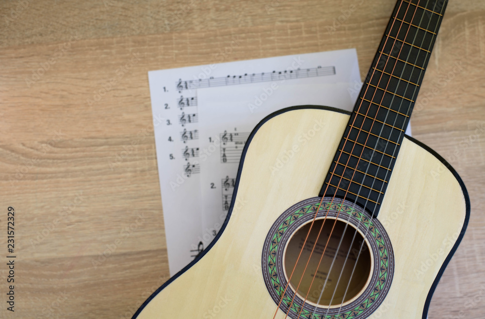 Fototapeta premium Classical guitar with tablature on the desk. Sun light. Top View