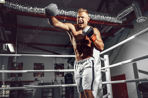 Boxer. Confident young boxer punching, training on the boxing ring