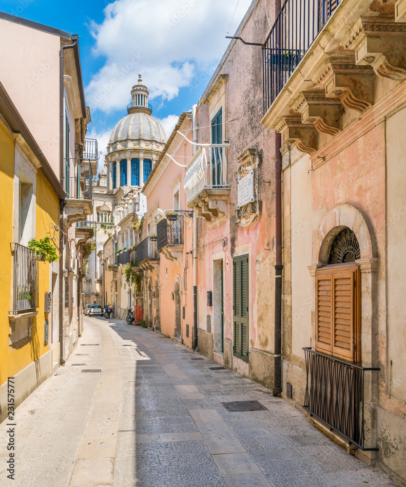 A narrow and picturesque road in Ragusa Ibla with the dome of Saint George Duomo. Sicily, southern Italy.
