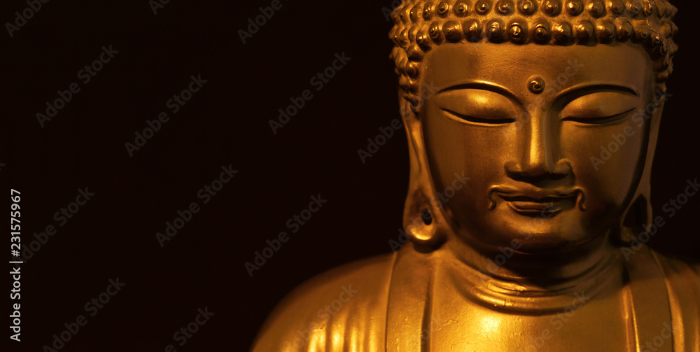 Golden Buddha statuette in the act of meditating (on black background with copy space)