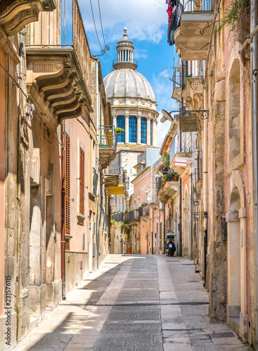 A narrow and picturesque road in Ragusa Ibla with the dome of Saint George Duomo. Sicily, southern Italy.