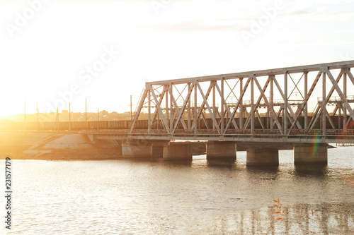 Fototapeta Naklejka Na Ścianę i Meble -  The sunset train passes the railway bridge