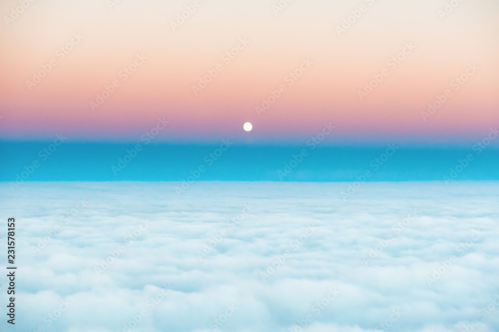 Sky and clouds at sunset with full moon rising, aerial view from plane
